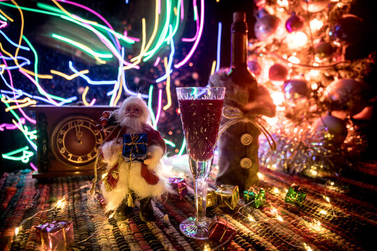 Red wine in crystal glass with bottle on colorful carpet with creative New Year artwork decorations. Copy space