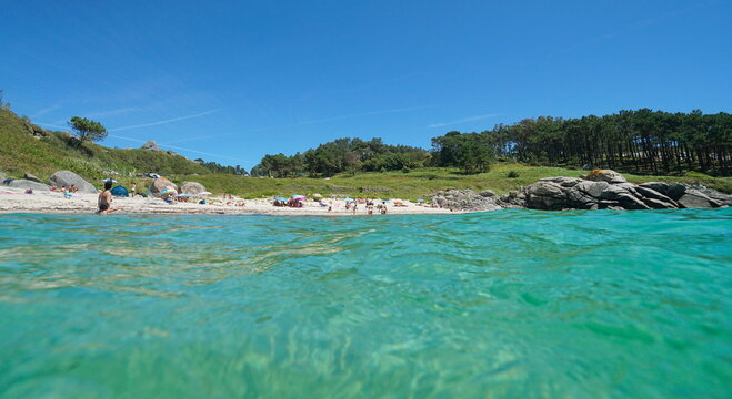 Spain Galicia coastline, beach with tourists in summer vacations seen from water surface, Atlantic ocean, Bueu, Pontevedra province, Praia do Ancoradoiro