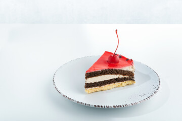Tasty biscuit cake with cherries on white plate on white background