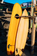 Retro two yellow surfboards for rent on the beach. Multicolored surf boards different sizes on stand in rental place on Bali, Indonesia
