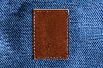 Square piece of leather sewn onto the jeans. Brown leather. Copy space