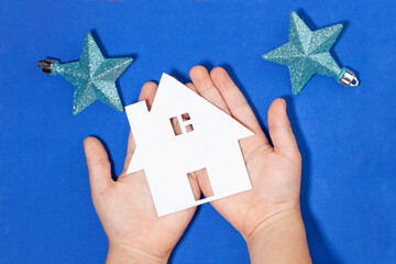 A child holds a house cut out of paper in his hands. Conceptual photography - a housewarming party....