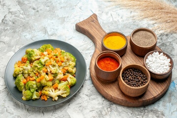 Side view of healthy vegetable salad different spices on cutting board on white background