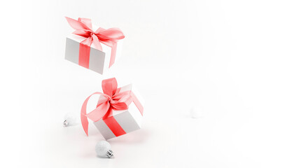 Christmas gift. White gift box with red ribbon, New Year balls in xmas composition on white background for greeting card. Winter festive composition with copy space.