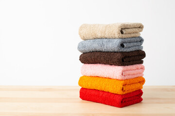 Stack of colorful towels on wooden table. Fresh new fluffy towels