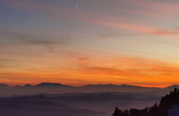 Fototapeta premium Tramonto sulle montagne, colline e valli dell'Appennino con la luna nel cielo