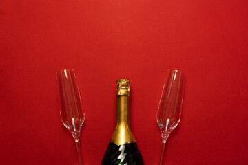 Bottle of champagne  or sparkling wine and couple of glasses on red background, top view.