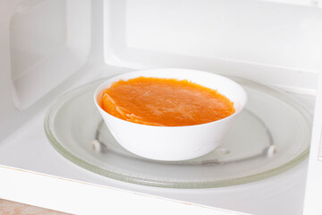 Frozen pumpkin soup in the microwave. Frozen food. Frozen soup.
