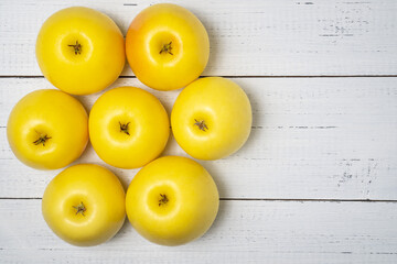 Group of sweet and juicy yellow golden apples on a wooden table with empty space. Healthy snack.