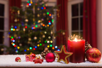 Christmas red candle with decorations and fir tree isolated on lights background.