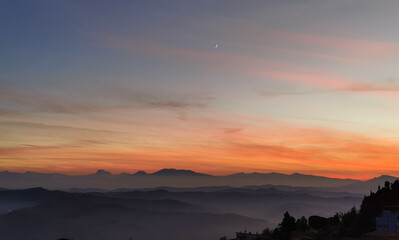 Fototapeta premium Tramonto sulle montagne, colline e valli dell'Appennino con la luna nel cielo