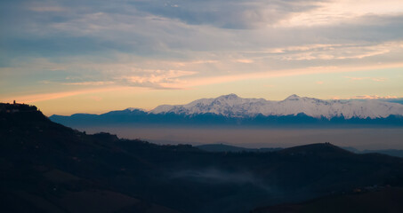 Fototapeta na wymiar Montagne innevate degli Appennini in un luminoso tramonto invernale