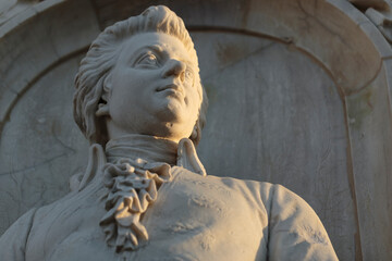 Stone figure of musical genius, composer Wolfgang Amadeus Mozart, in a monument from 1898, closeup horizontal view. - obrazy, fototapety, plakaty