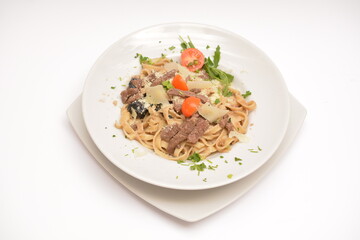 Pasta with beef, prunes and parmesan cheese on a white plate. Located on a white background. Can be used in the restaurant menu.