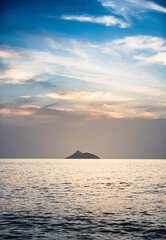 Fototapeta na wymiar Sea with small island against cloudy sky