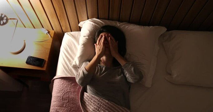Worried sleepless woman in 30s lying in bed unable to sleep