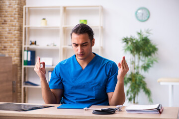 Young male doctor being extremely tired after night shift