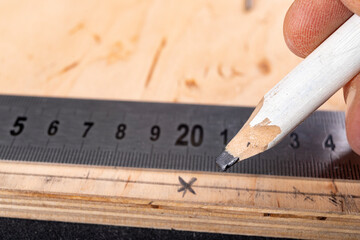 Metal measuring tape and pencil for drawing on wood. Minor carpentry work in the workshop.