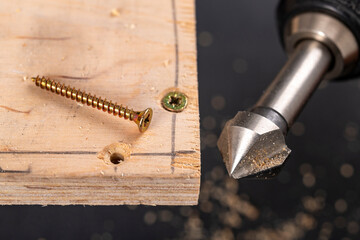 Countersinking holes for metal carpenter's screws. Minor carpentry work in the workshop.