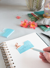 Empty spiral notebook with a dotted pencil held by a woman hand and an important note clamped at the top of it.