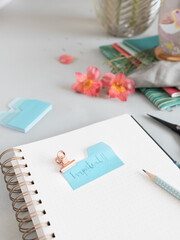 Empty spiral notebook with a dotted pencil and an important note clamped at the top of it. A stack...
