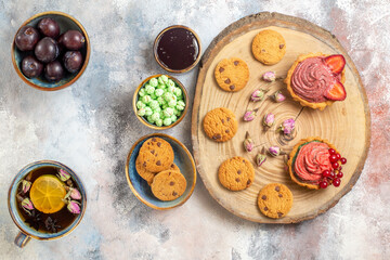 top view delicious creamy cakes with tea on light desk candy photo biscuit sweet