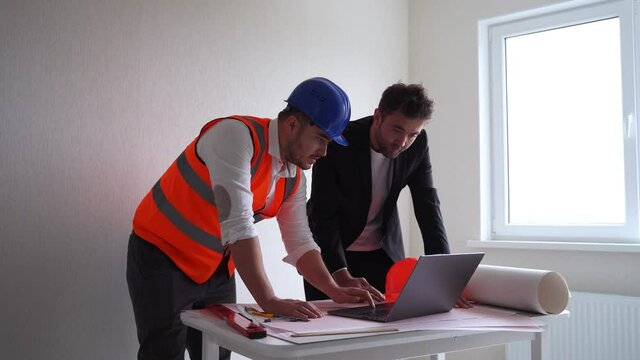 man contactor and entrepreneur using laptop..Businessman and man architect browsing drafts on laptop while working on project in workplace together