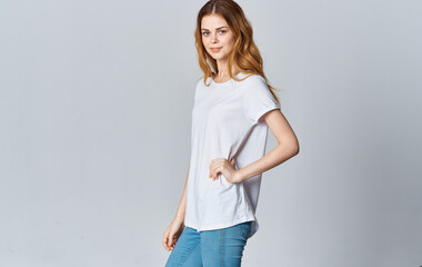 Beautiful woman in a white T-shirt and jeans on a gray background gestures Copy Space