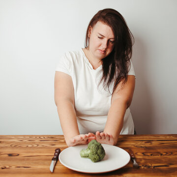Overweight woman refusing small piece of vegetable