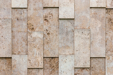 beige-gray wall of natural textured stone blocks, irregularly arranged