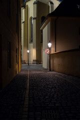 street lights on an illuminated street and pebbles on the ground in the center of the old town of prague at night in the czech republic