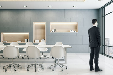 Businessman standing in meeting room interior with city view