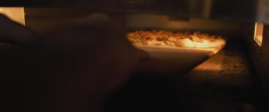 Italian al taglio pizza with fried onions placed in the hot oven. Slow motion.