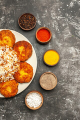 top view fried cutlets with cooked rice and seasonings on dark background food dish photo