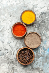 Vertical view of different spices in brown bowls on gray background