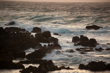 Fototapeta na wymiar Ocean crashing onto a rocky shore at sunset