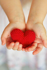 child's hands holding knitted heart
