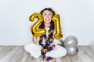 A brunette woman with a Christmas costume and pajamas with her eyes close and a funny face excited for the New Year. 2021 New Year's Eve party at home concept