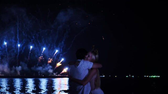 Happy Caucasian Ethnicity young couple enjoying fireworks display in Fireworks Festival During night at Beach side. New Year's Eve, Celebration Event, Date Night- Romance Concept