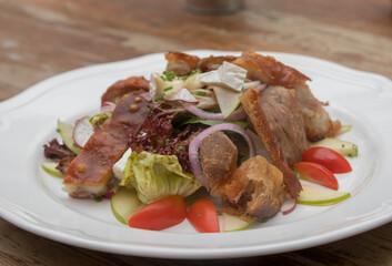 Mix leaves with pork roast slices, crackling, apple, Camembert cheese, cherry tomatoes, and apple vinaigrette