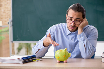 Young underpaid male teacher in the classroom