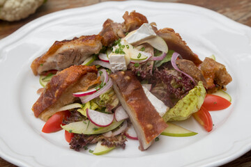 Mix leaves with pork roast slices, crackling, apple, Camembert cheese, cherry tomatoes, and apple vinaigrette