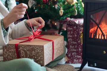Woman in pajamas unwrapping gift box on Christmas morning