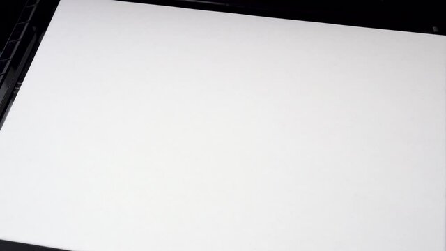 Hand puts a blank sheet of office paper into an open printer close up. Business financial documents concept