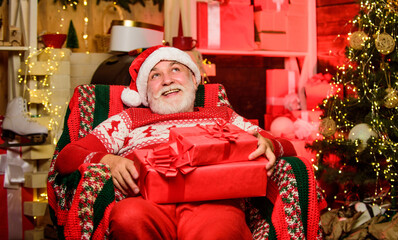 Obraz na płótnie Canvas Santa Claus relaxing in arm chair. Bearded senior man Santa Claus. Legend about Santa Claus. Merry christmas. Delivering gifts. Presents for family. Traditions concept. Elderly grandpa at home