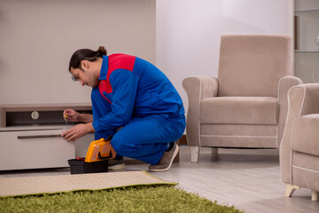 Young male contractor repairing drawyer indoors