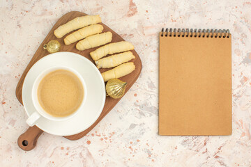 Coffee break with delicious mutakies on wooden cutting board and notebook on mixed color background