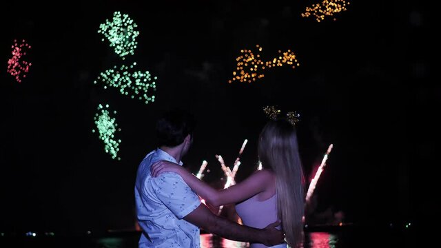 Happy Caucasian Ethnicity young couple enjoying fireworks display in Fireworks Festival During night at Beach side. New Year's Eve, Celebration Event, Date Night- Romance Concept. Slow motion
