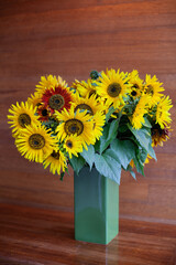 Bright yellow sunflowers in full bloom in a green ceramic vase