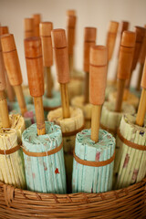 Collection of paper and bamboo decorative umbrellas in a cane basket